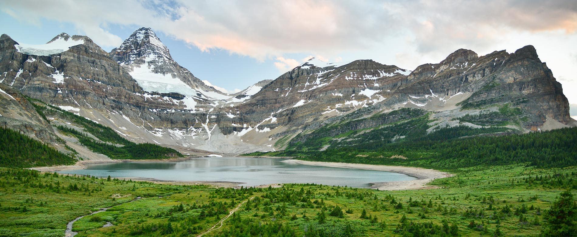 Iconic Mount Assiniboine rising above turquoise lake and alpine meadows