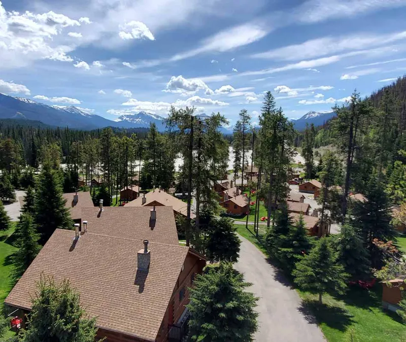 Becker's Chalets nestled among towering pines with snow-capped peaks rising beyond.