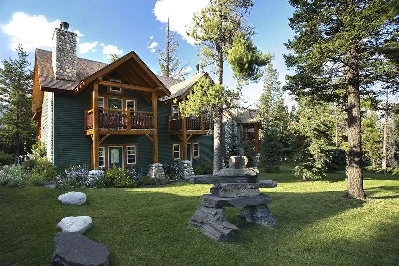 Buffalo Mountain Lodge cabin with log and timber construction, stone fireplace chimney, and coniferous forest backdrop.