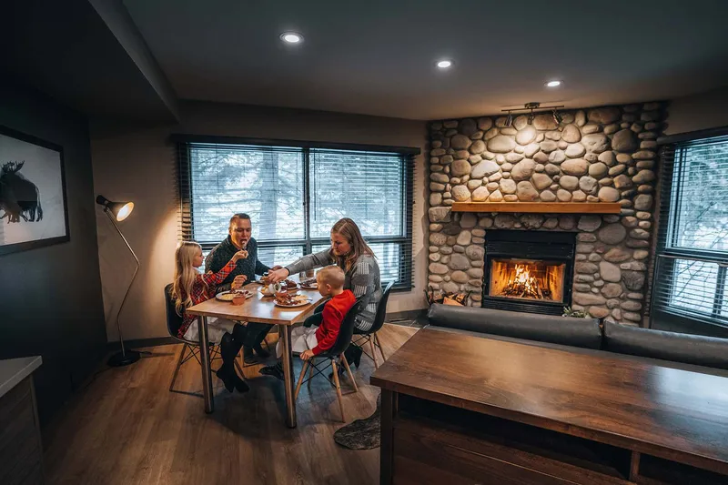 Family dining at Buffalo Mountain Lodge with stone fireplace and forest views.