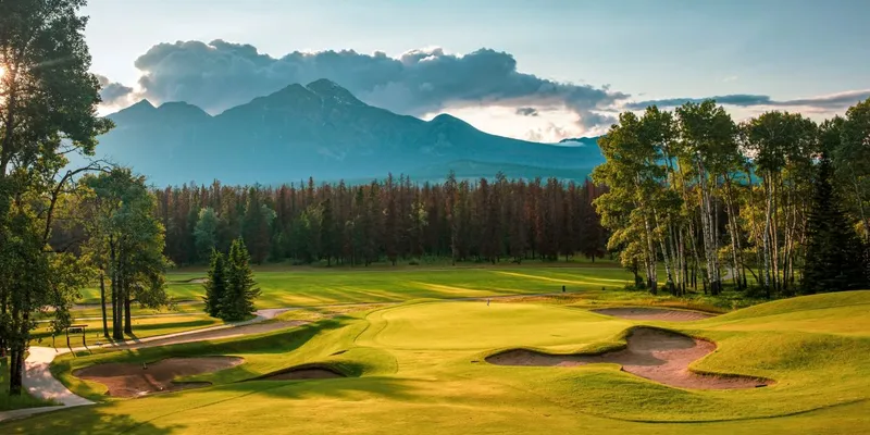 Golf course at Fairmont Jasper with mountain peaks and forested fairways in background.