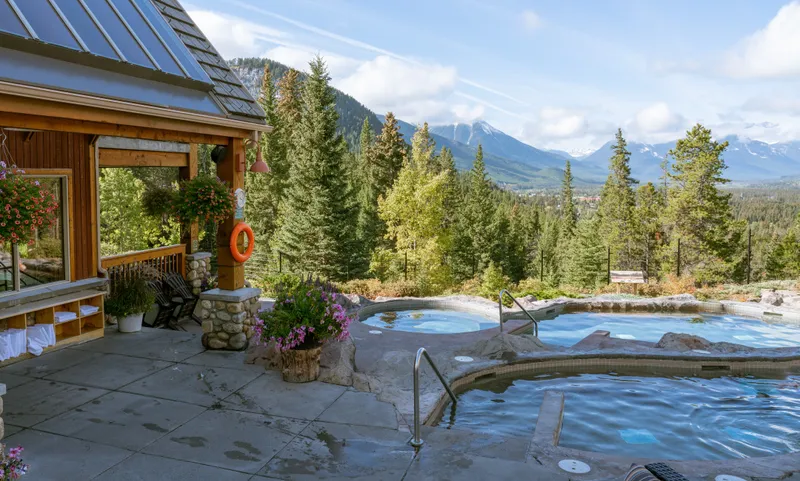 Hot springs pools at Hidden Ridge Resort with mountain vista and log lodge behind.