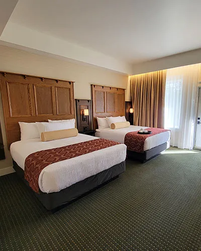 Kilmorey Lodge double queen room with wood headboards, burgundy bed runners, and patio doors overlooking the lake.