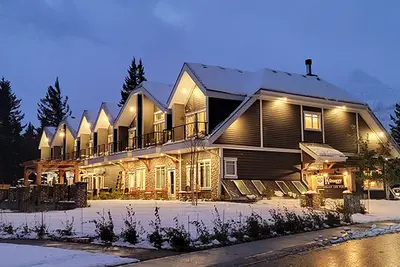 Kilmorey Lodge's lit contemporary exterior with peaked gables overlooks snowy grounds at dusk.