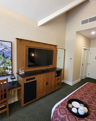 Kilmorey Lodge king room with wood-framed entertainment center, cream walls, and mountain landscape artwork.