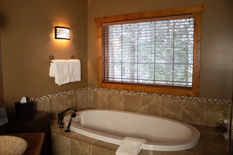 Prairie Creek Inn treehouse bathroom with soaking tub, tile wainscoting, and forest views.