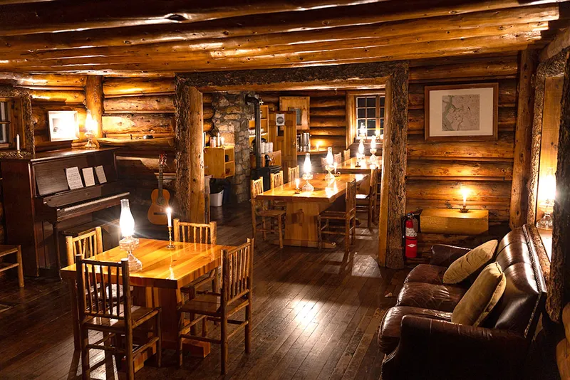 Rustic dining room with log beams, piano, and candlelight